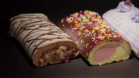 slider panning shot of ice cream froster swiss cake rolls collection with black background oreo blackberry neapolitan mix with sprinkles and mocca mocha flavors