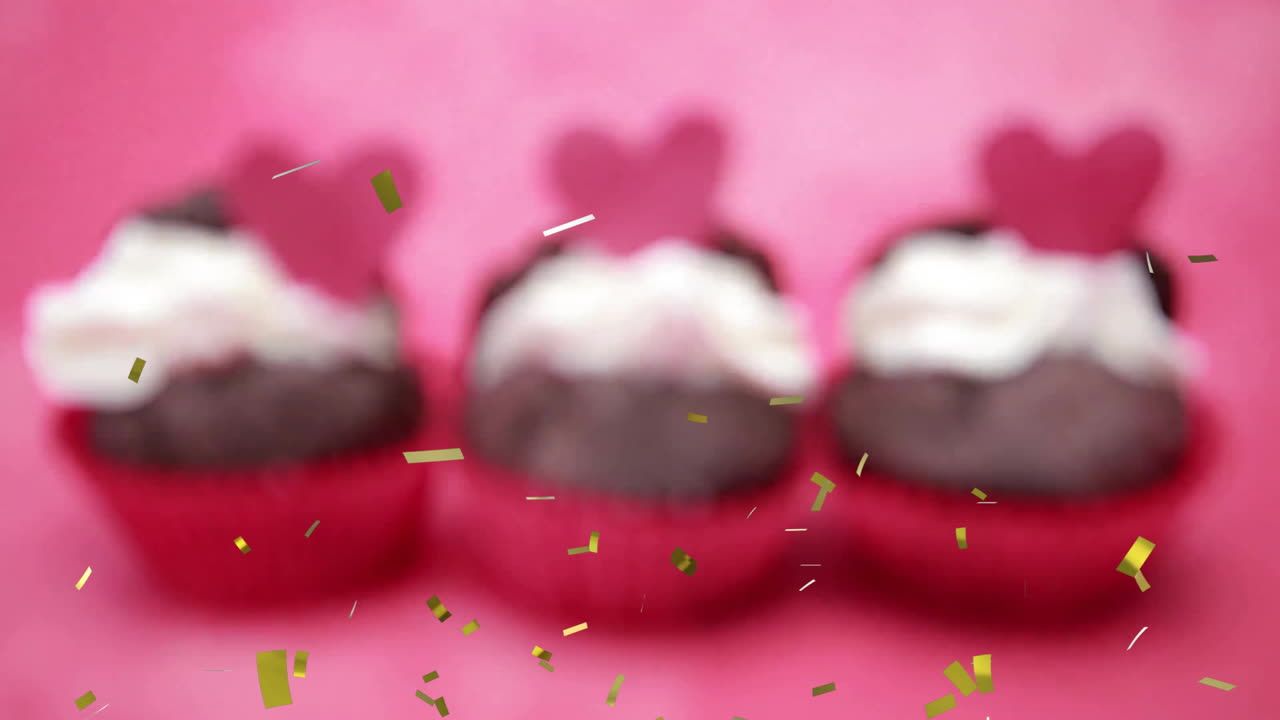 Cupcakes with heart toppers and whipped cream, confetti falling animation over pink background