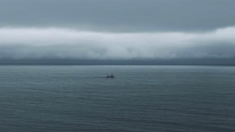 Overflying-The-Calm-Waters-Of-Saint-Lawrence-River-With-A-Fishing-Boat-Sailing-In-The-Distance-On-A-Cloudy-Day-In-Quebec,-Canada