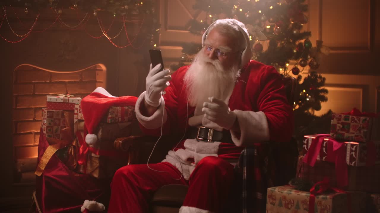 Dancing Santa Claus with headphones and a mobile phone in his hands. Listen to music online. Jerky and dynamic songs