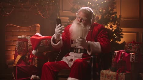 dancing santa claus with headphones and a mobile phone in his hands. listen to music online. jerky and dynamic songs