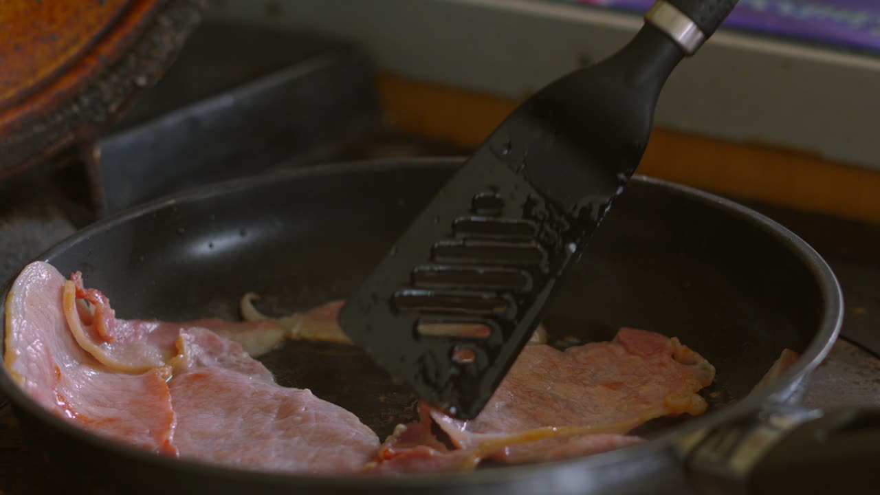 Chef Turning Over Bacon Slices with Fat Rind and Bubbling Hot Oil. Cooked Breakfast Morning Food.