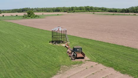 Low-panning-aerial-shot-of-an-empty-corn-silo-and-old-farm-truck-in-the-rural-farmland-of-Minnesota