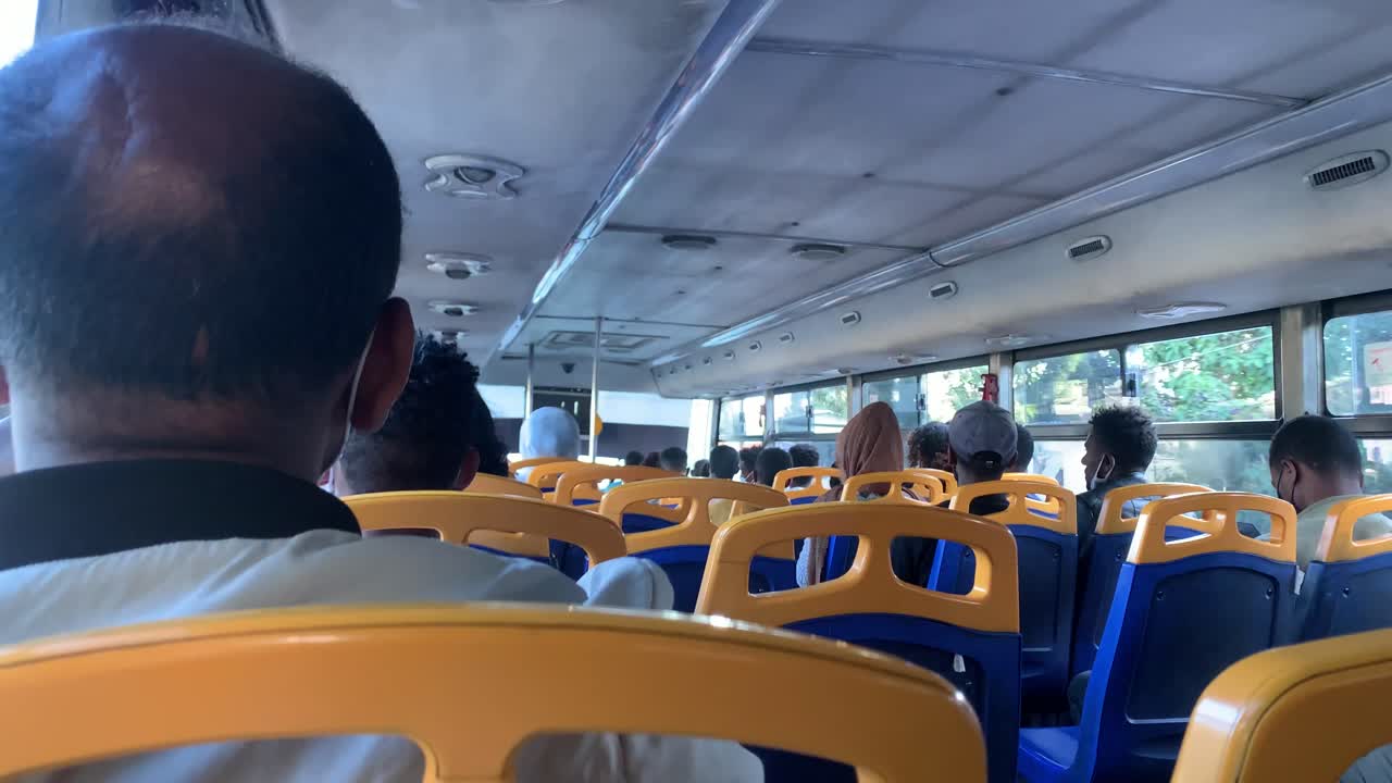 People setting quietly inside the second floor in double deck bus