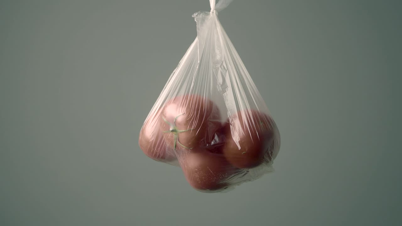 Tomates rojos frescos colgando en una bolsa de plástico transparente