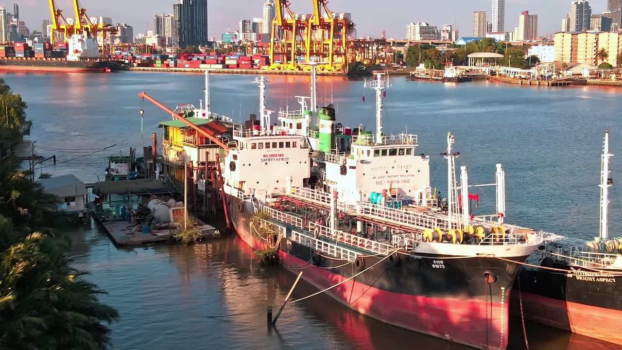 View of cargo ships and trees near the river in Bangkok during the day