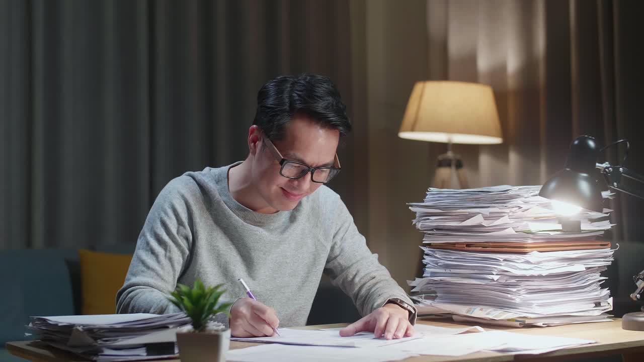 Smiling Asian Man Enjoys Working With Documents At Home
