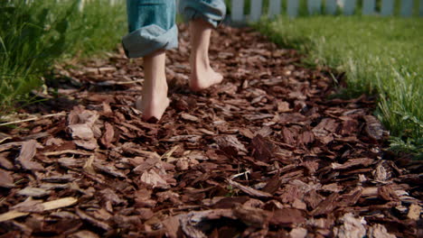 barefoot child walking on a wood chip path