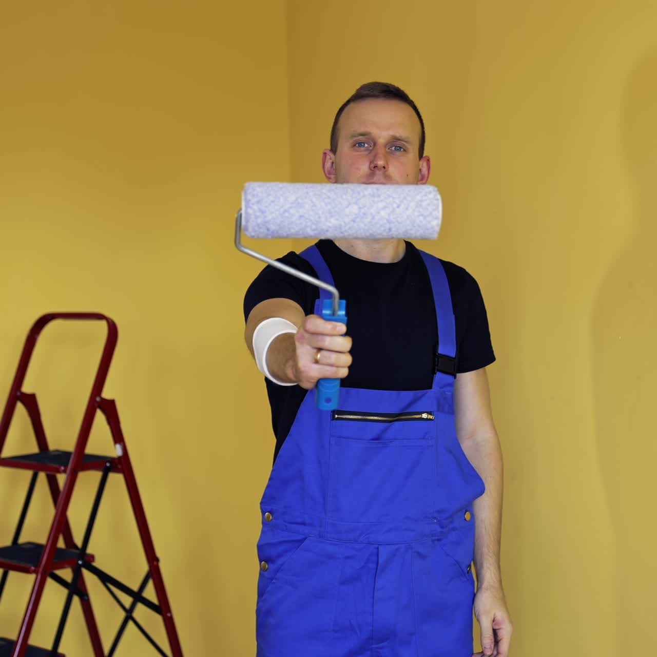 Portrait of a handsome man worker with tool for paint. Painter holding new paint roller before starting interior decoration. Offering professional painting services