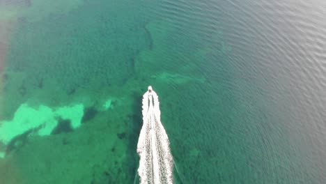antena alta: tubería detrás del barco sobre los arrecifes de coral en agua verde clara