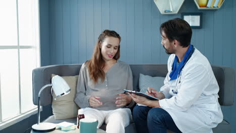mujer embarazada sonriente hablando con el médico en la clínica prenatal.