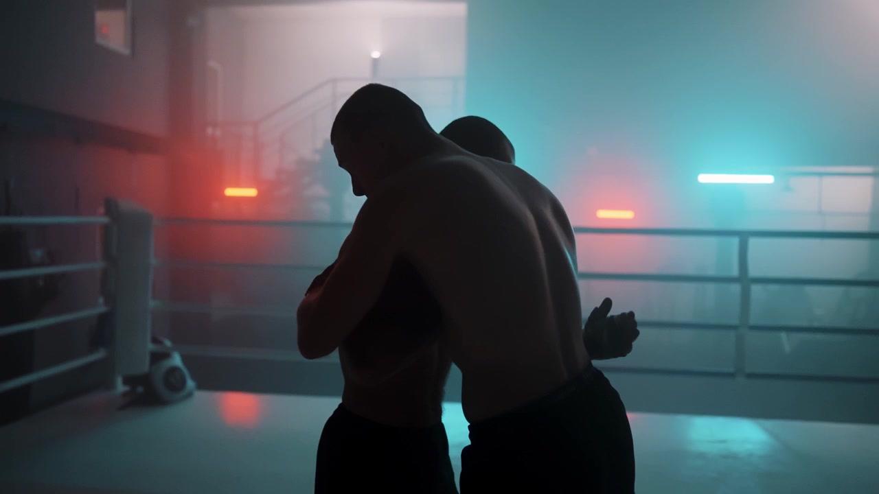 Sagome di lottatori in clinch in un ring di pugilato fumoso con luci al neon