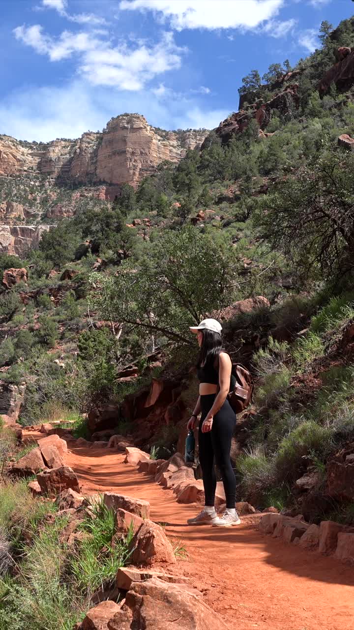 Donna con zaino in escursione su un sentiero di canyon di roccia rossa