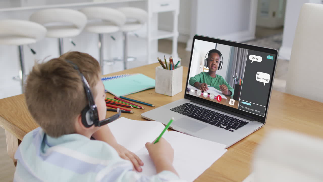 Schoolboy using laptop for online lesson at home, with schoolboy and webchat on screen