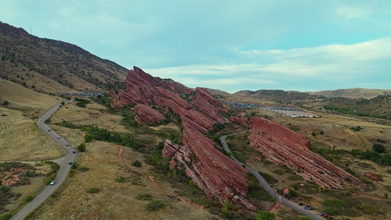 Drone establishing road leading to dramatic red rock cliffs and open amphitheatre landscape near Denver Colorado in bright daylight