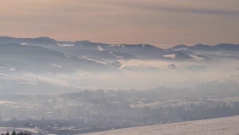 look out towards fog and haze covered village in valley with industry in winter