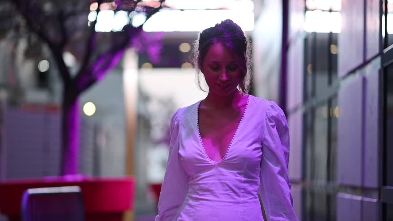 Mulher de vestido branco posando em Cannes sob luzes púrpuras, França