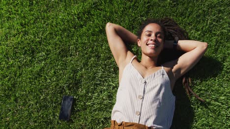 Portrait-of-african-american-woman-lying-on-grass-looking-at-camera-smiling