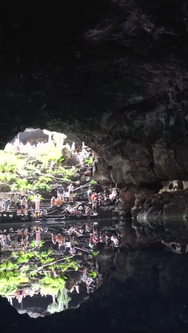 visitors in a volcanic cave with a reflection pool