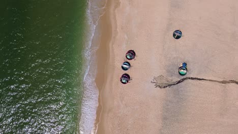 drone shot moving forward over round fishing boats along the shoreline at mui ne beach, vietnam.