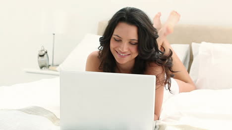 Brunette-using-her-laptop-while-she-lies