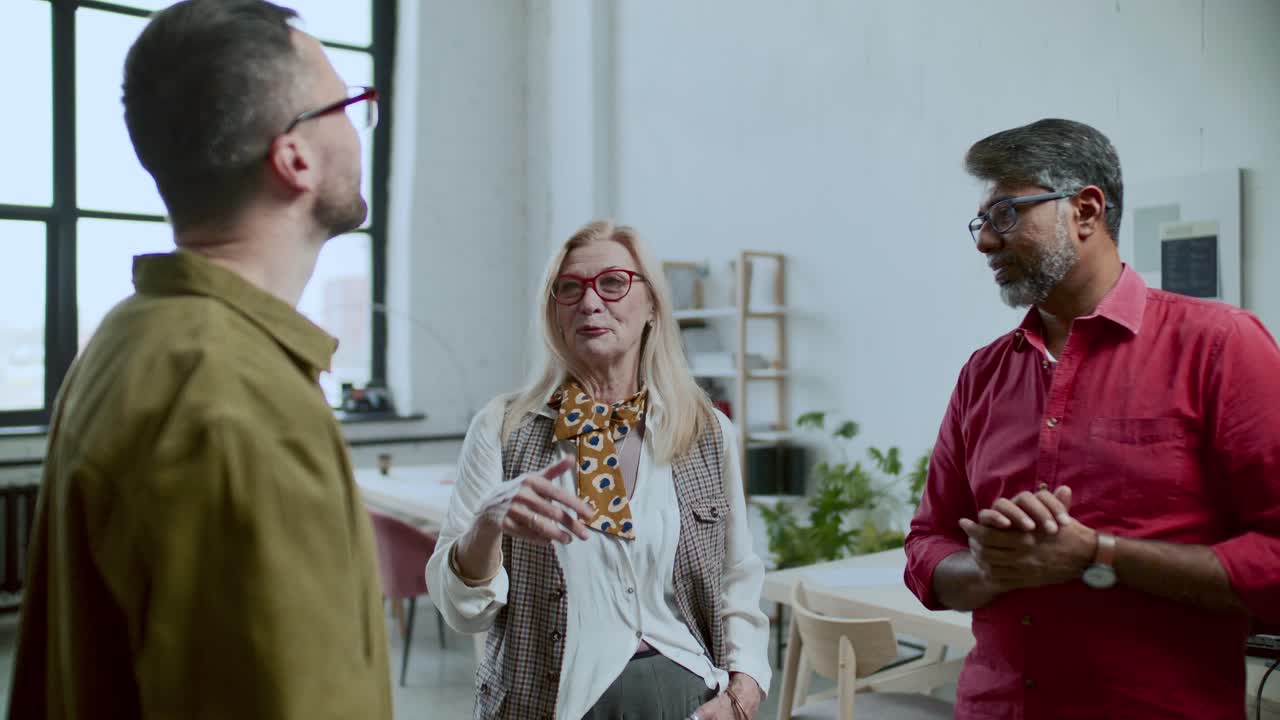 Elegant Senior Businesswoman Talking to Two Male Colleagues in Modern Office