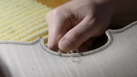 macro close up of artisan luthier maker work on new classic handmade raw violin smooth edge in waist and purfling rasp in workbench of workshop in cremona italy 4k video