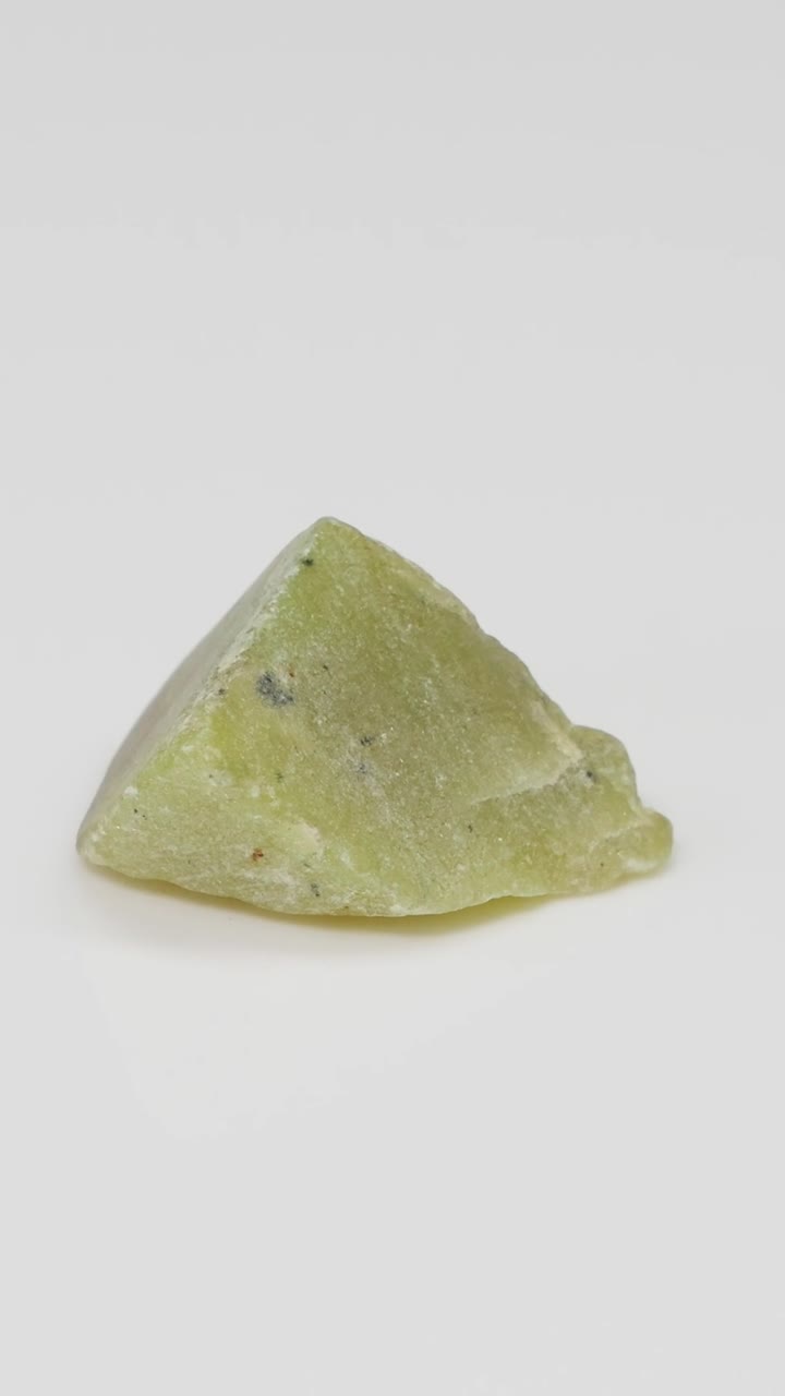 una piedra de jade girando en una superficie blanca