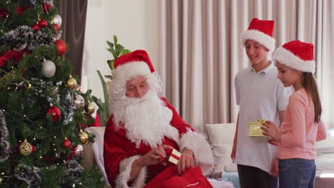 Happy-caucasian-siblings-with-santa-claus-giving-presents-at-christmas