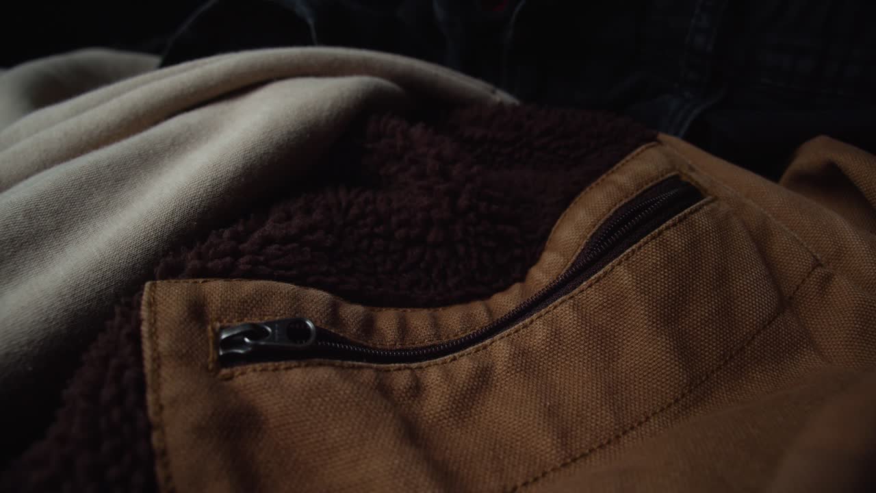 Casual jacket of brown color material laying on couch, dolly backward shot