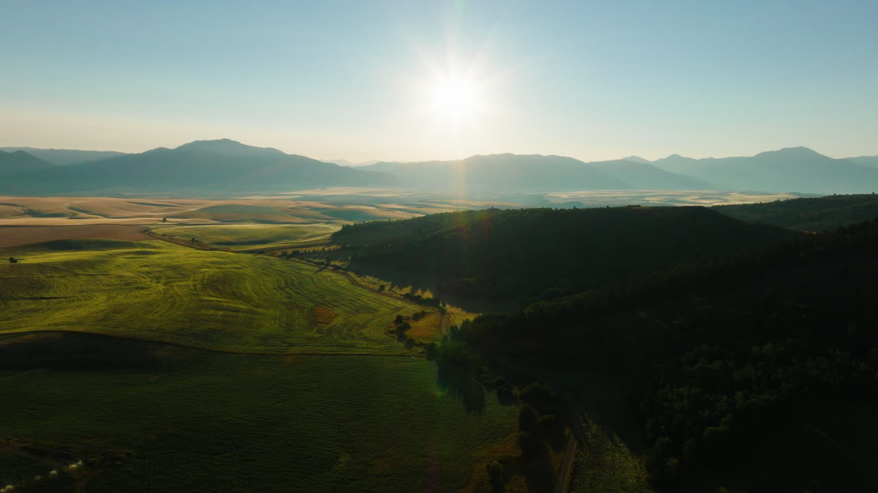 Sunrise or sunset over a vast mountain valley with green fields
