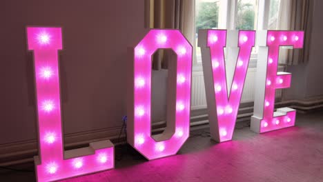pink neon love sign letters on the floor at a wedding event.