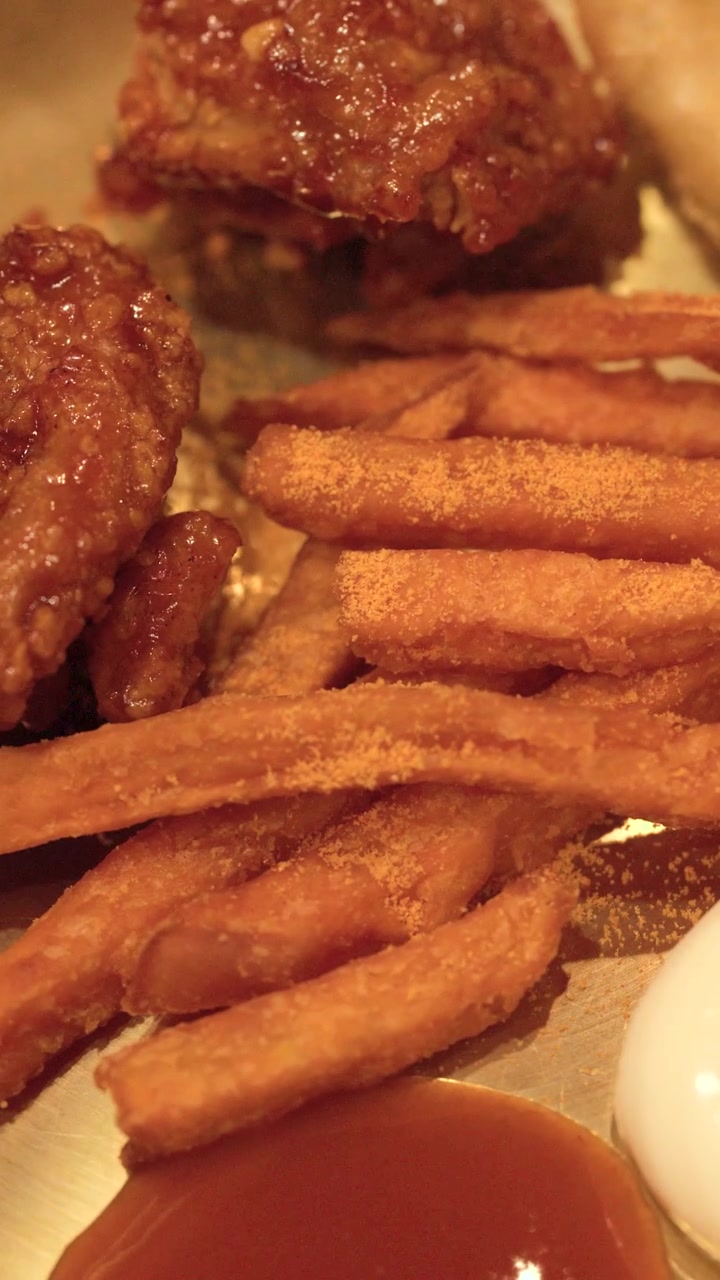Toma macro de pollo picante glaseado, patatas fritas y salsas para mojar en un plato de latón