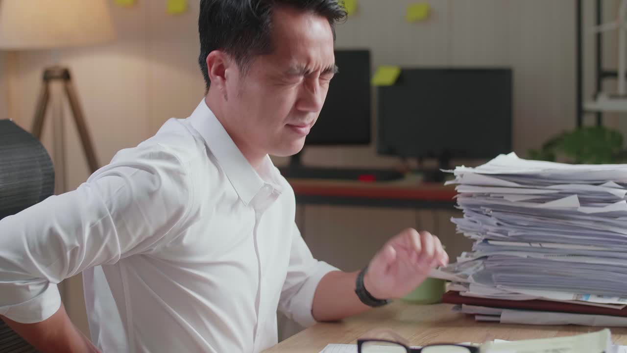 사무실에서 문서로 열심히 일하는 동안 허리 통증이 있는 아시아 남자의 클로즈업