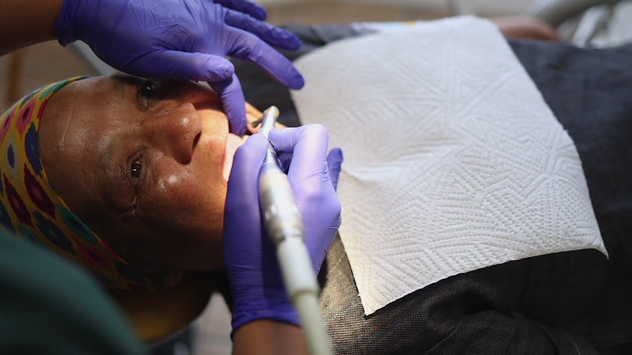 Elderly woman in dental chair, dentist polishes her teeth, close up