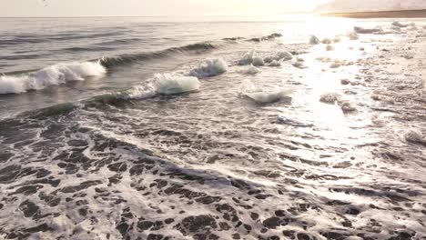 ice chunks scatter along the shore as waves roll in on iceland’s black sand beach