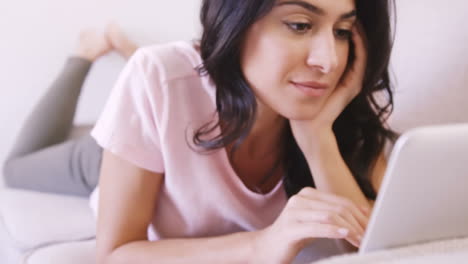 woman lying on a sofa using her laptop