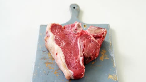 Raw-steak-garnished-with-herb-on-chopping-board