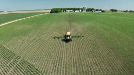 aerial, tractor spraying pesticide on fresh crops in rural agricultural farm field