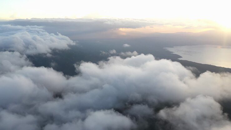 Aerial hyperlapse of footage taken above the clouds with golden hour and a large body of water in the distance