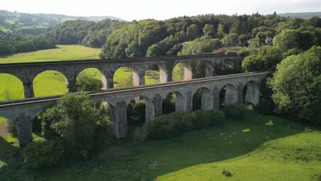 People-crossing-canal-towpath-over-Chirk-Aqueduct,-Railway-Viaduct-in-background---aerial-drone-anti-clockwise-rotate-and-pan---Welsh,-English-border,-Sept-23