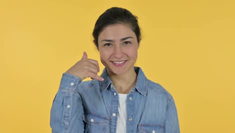 call me sign by young indian woman, yellow background