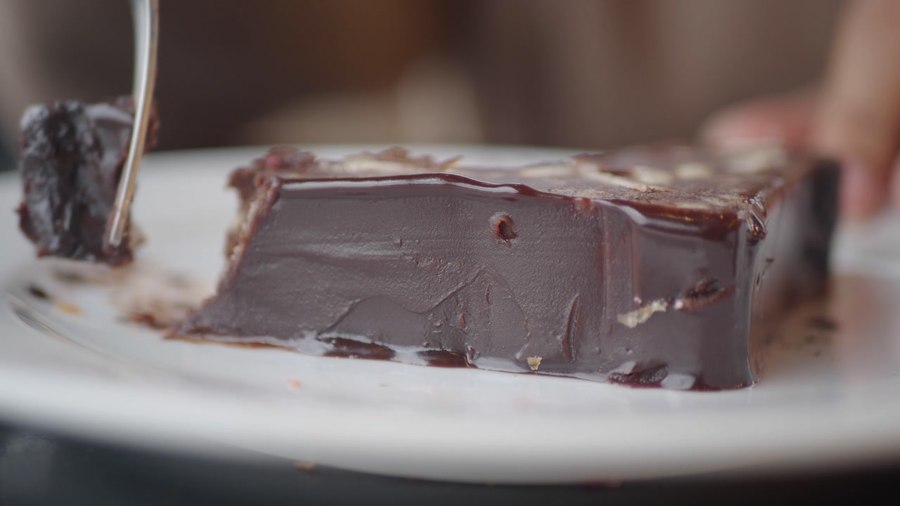 Close-up of a Fork Cutting into a Delicious Chocolate Cake Slice