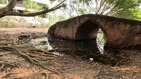 calm stream flows beneath an old brick bridge