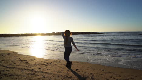 Kleines-Mädchen-Am-Strand-Wirft-Einen-Stein-Ins-Meer