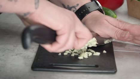 garlic is chopped on counter top with red onion, pepper and cucumber