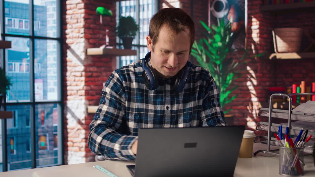 Uomo che si rilassa in appartamento, scrivendo messaggi agli amici sul laptop.
