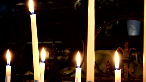 lights of burning white candles in a temple on a dark background