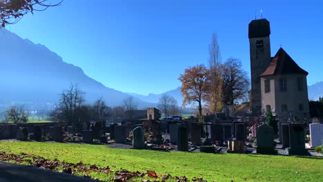 Antigua-Iglesia-Católica-Con-Cementerio-O-Cementerio-En-El-Suelo-Con-Cielo-Azul-Y-Montaña-Al-Fondo