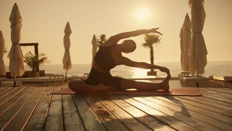 A-girl-in-a-black-sports-summer-uniform-does-stretching-and-bends-towards-one-of-her-legs-on-the-Red-Carpet-during-sunrise-on